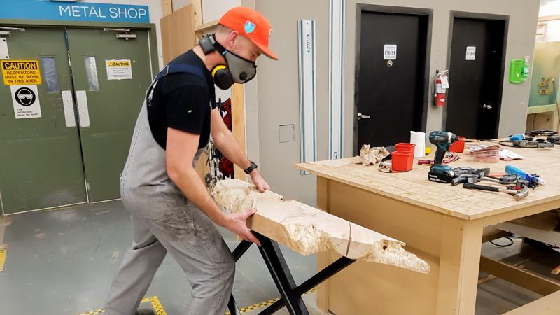 Image of a man putting a live edge maple top onto welded steel table legs