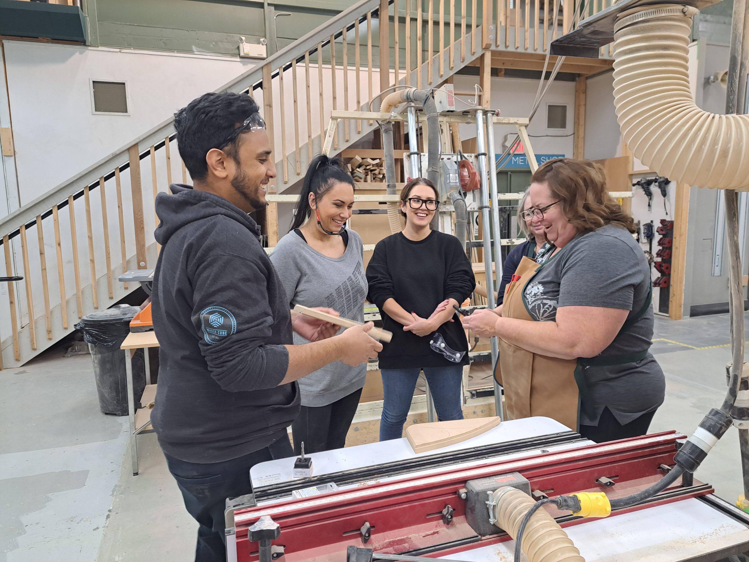 Image of three women being instructed on how to use a router table during a router table class workshop